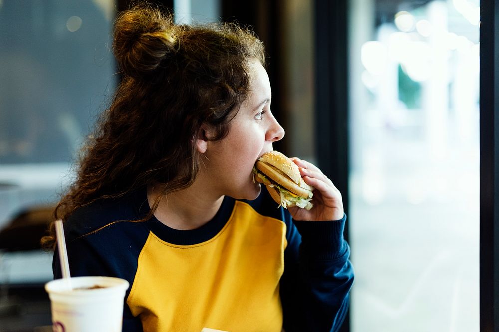 Close up of teenage girl eating hamburger obesity concept