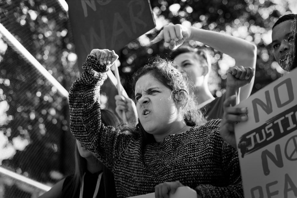 Closeup of angry teen girl protesting demonstration holding posters antiwar justice peace concept