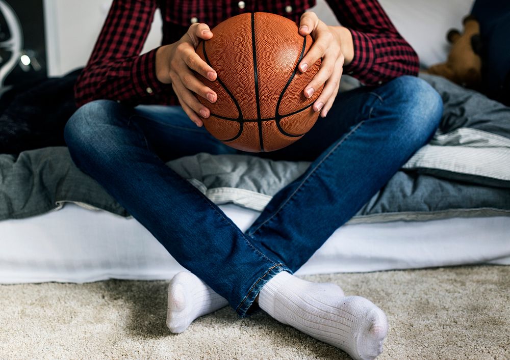 Teenage boy in a bedroom holding a basketball hobby aspiration and loneliness concept