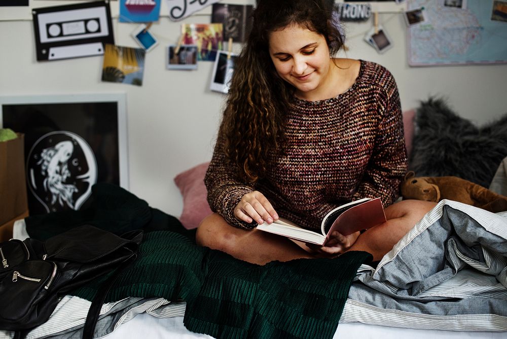 Teenage girl reading a book in a bedroom