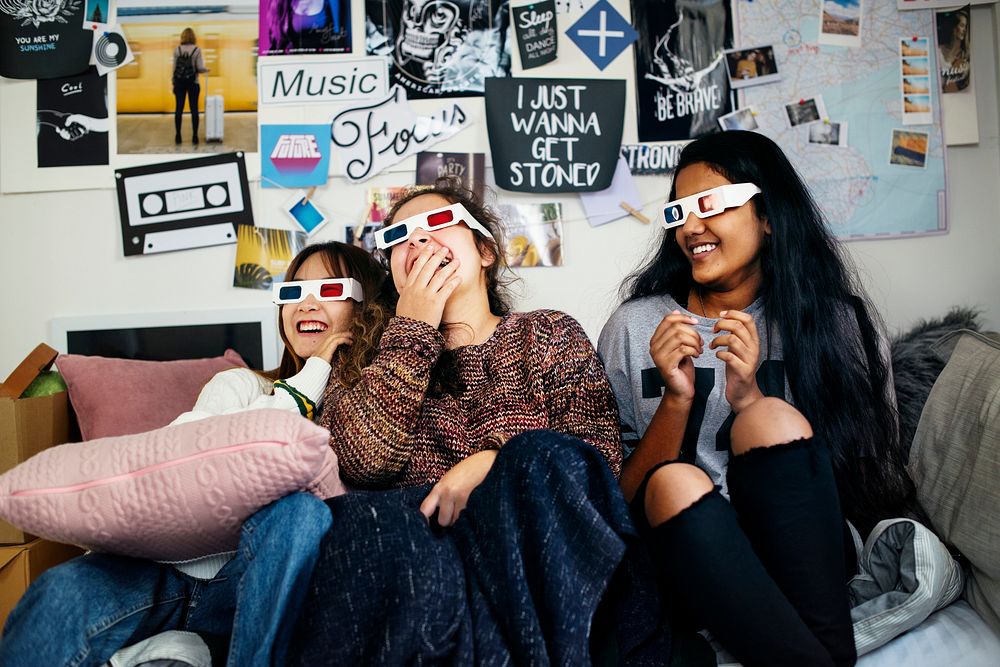 Teenage girls wearing 3d movie eyeglasses enjoying laughing and watching TV