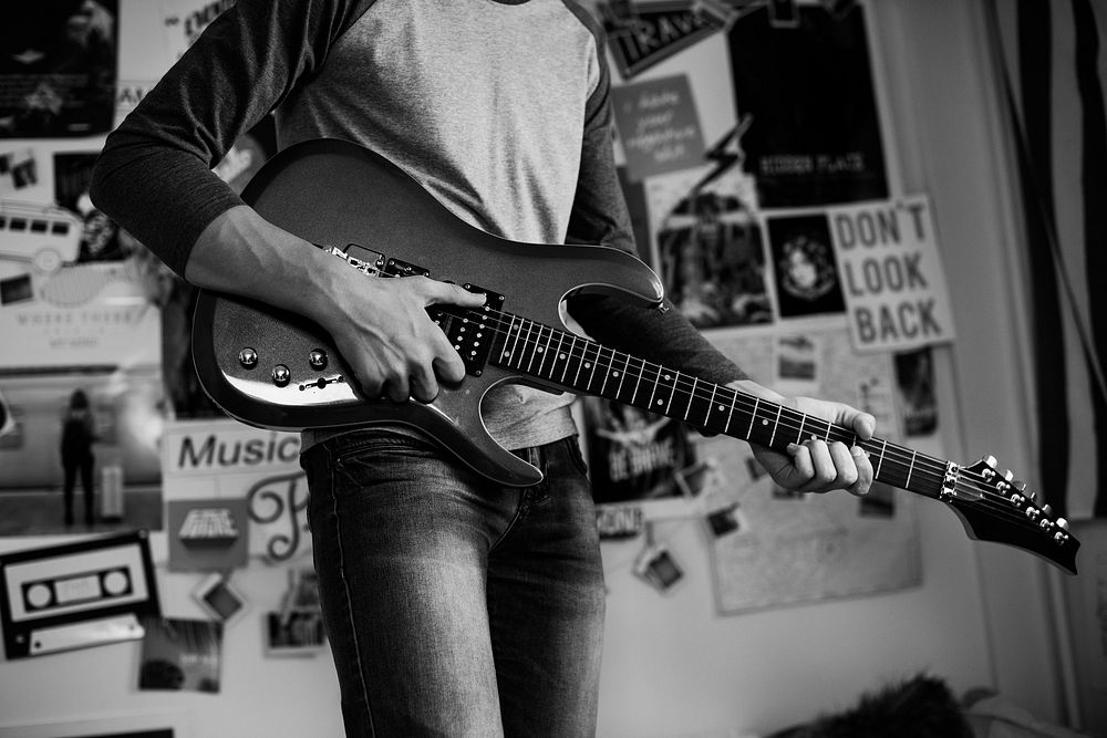 Teenage boy playing an electric guitar in a bedroom hobby and music concept