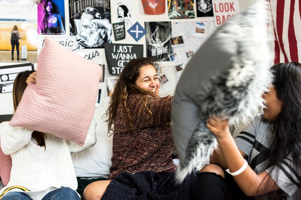 Teenage girls in a bedroom having a pillow fight