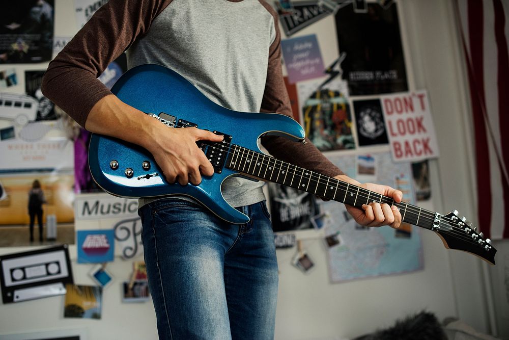 Teenage boy playing an electric guitar in a bedroom