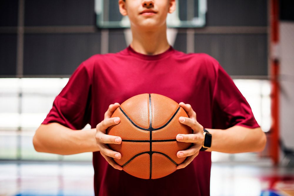 Teenage boy holding a basketball on the court