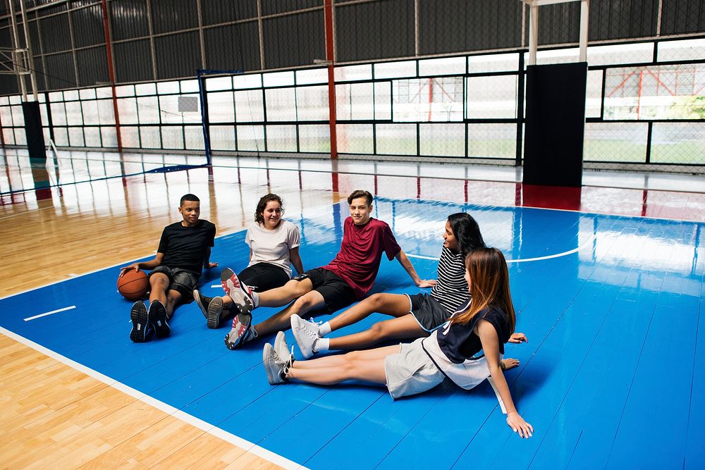 Group of young teenager friends on a basketball court relaxing