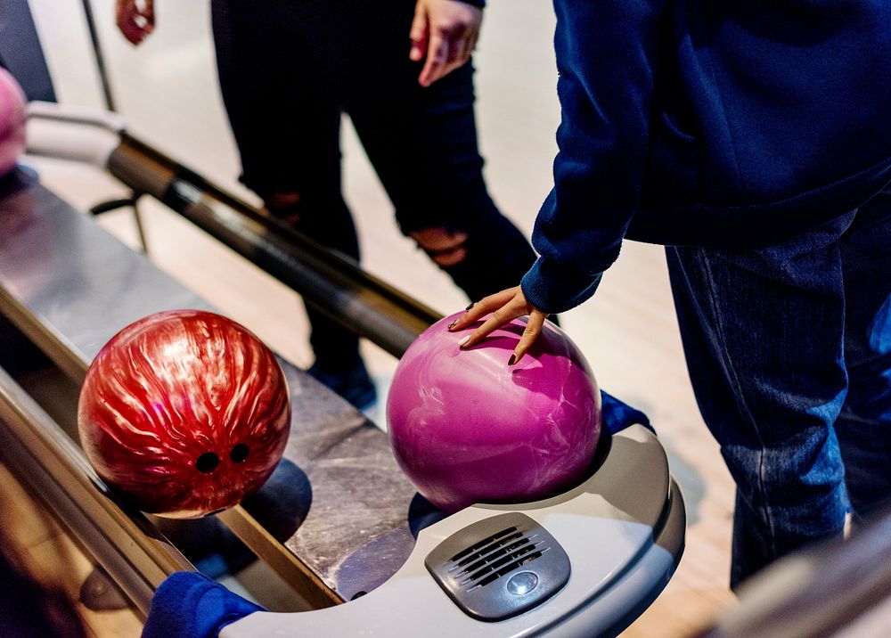 Girl picking up a bowling ball hobby and leisure concept