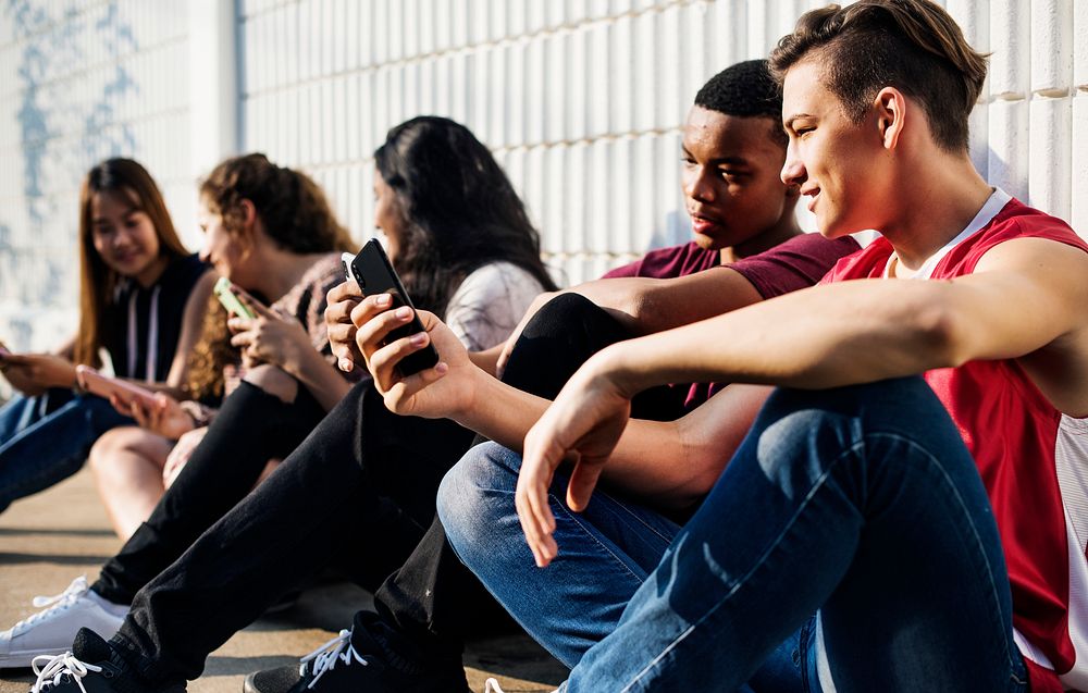 Group of diverse teenagers using phones