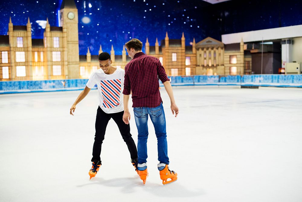 Friends having fun ice skating on the ice rink together