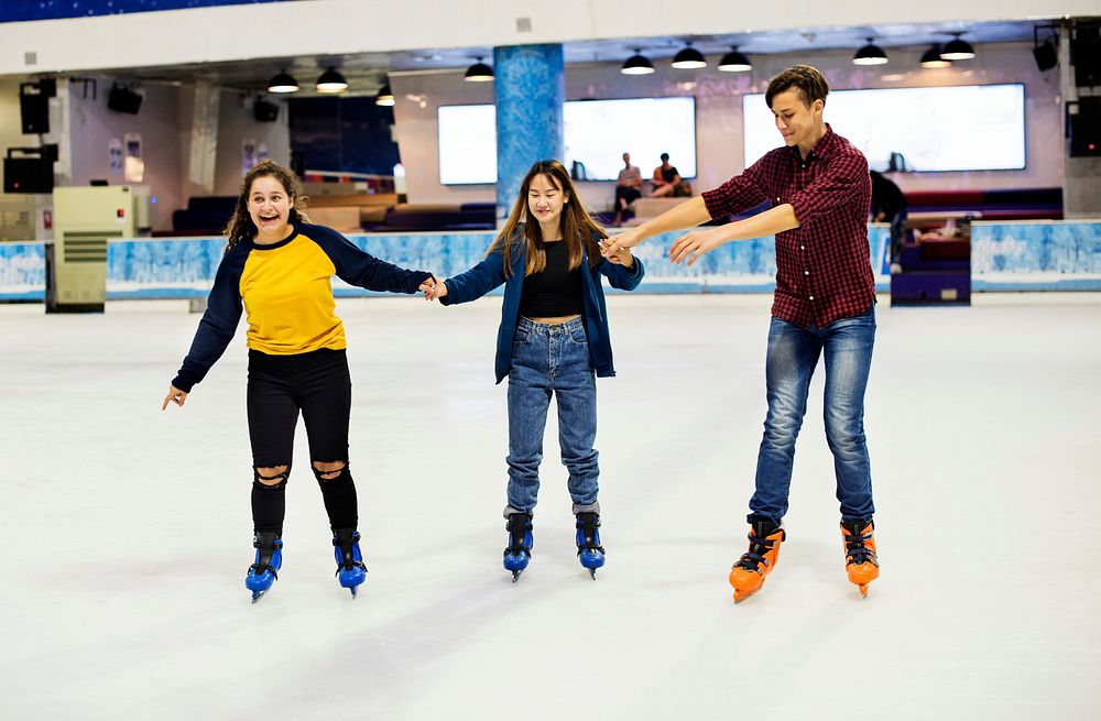Group of teenage friends ice skating on the ice rink together