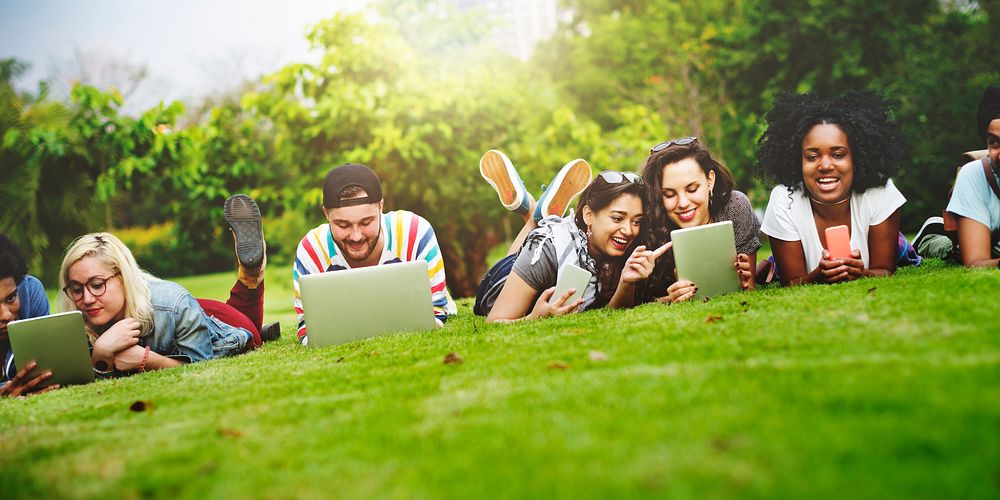 Group of friends on their mobile devices laying on the grass