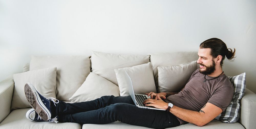 White man using laptop on sofa