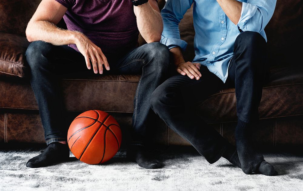 Man sitting together on a couch watching sport