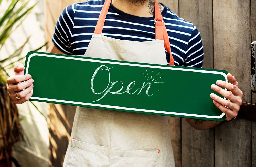 A person holding an "open" sign