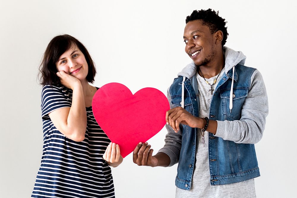 Happy smiling interracial couple holding a red heart