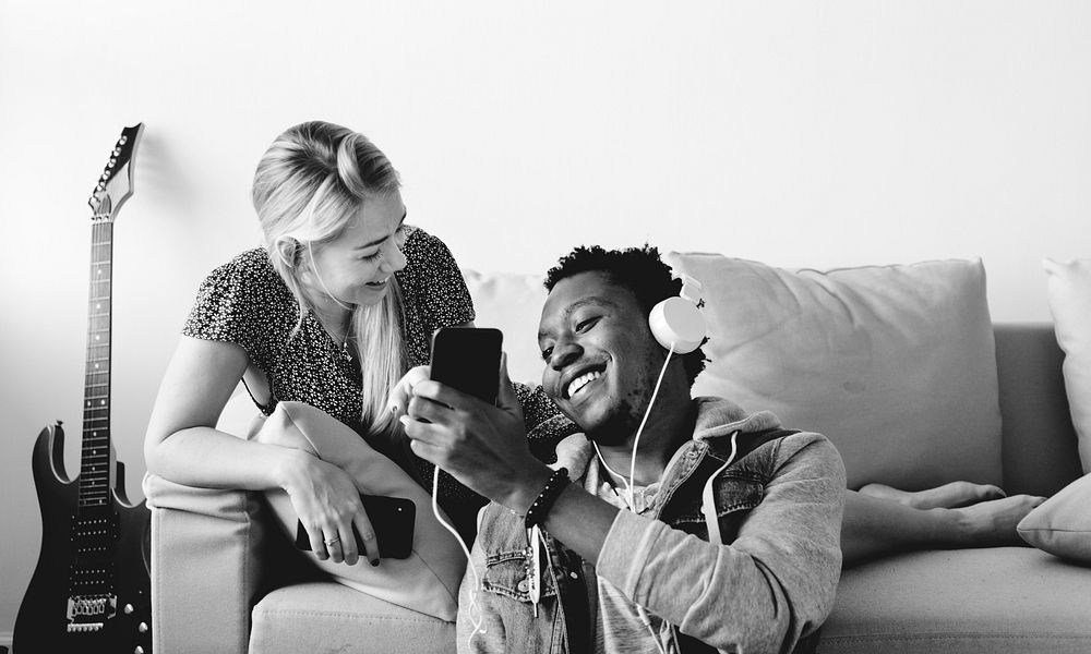 Interracial couple sharing music at home love, leisure and music concept