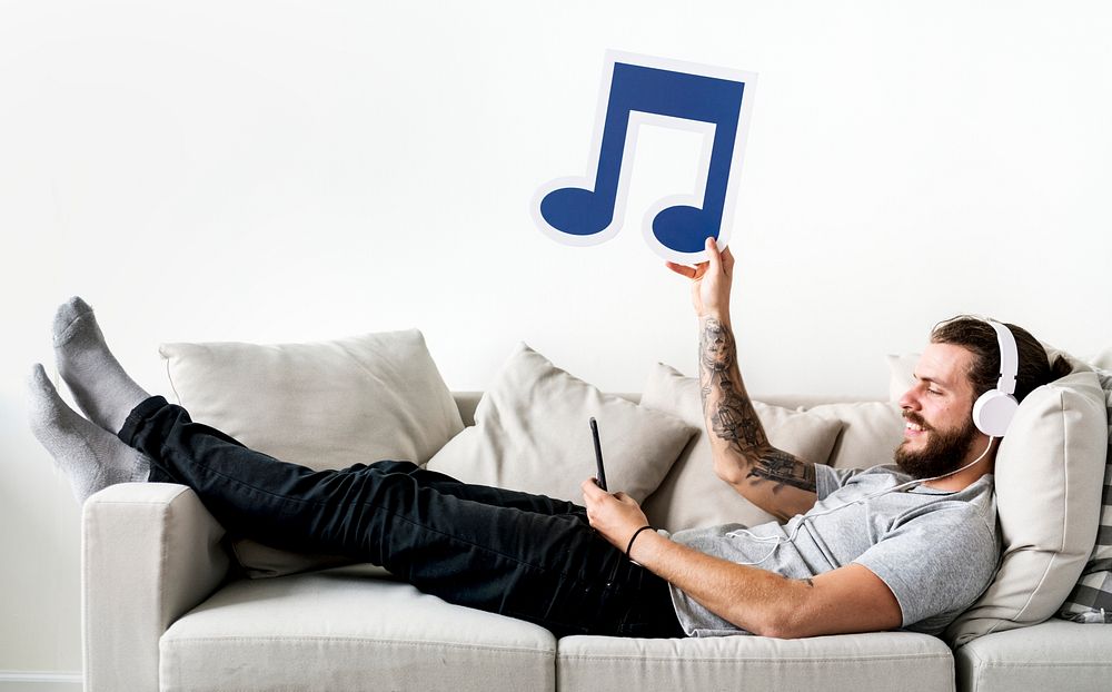 Caucasian man enjoying music at home holding musical note leisure and music concept