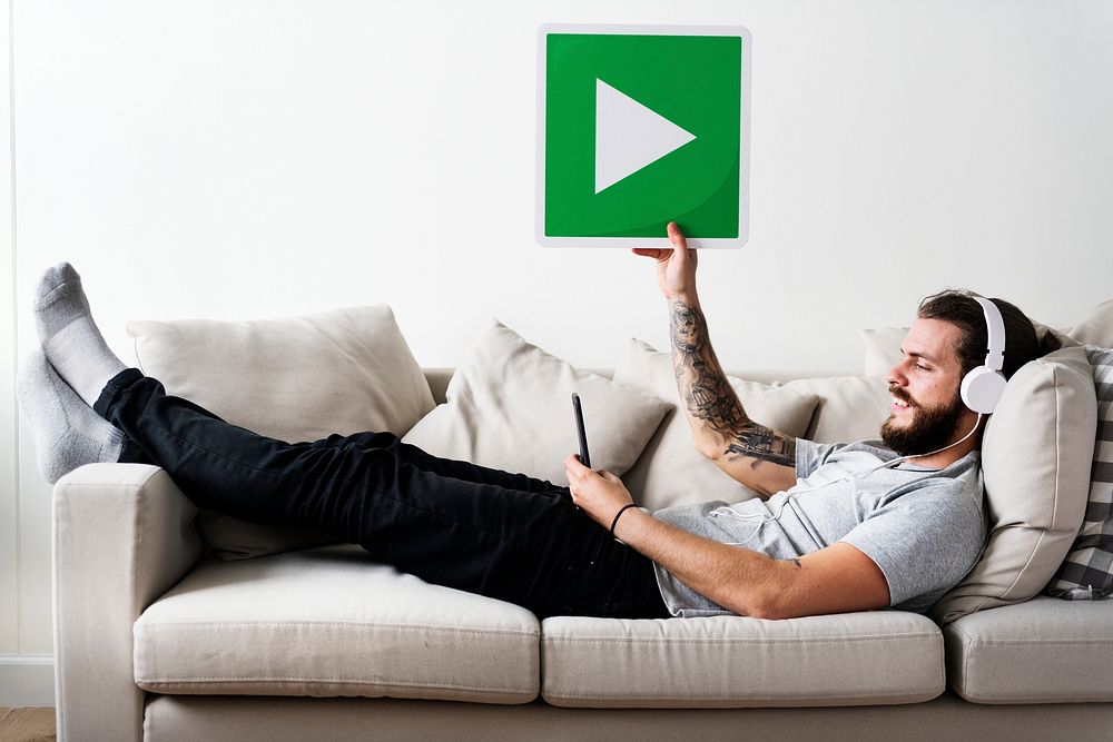 Caucasian man enjoying music at home holding a play button