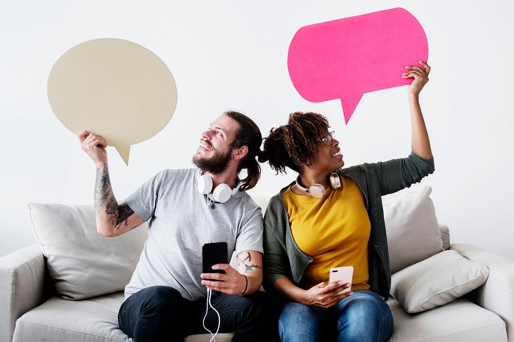 Interracial couple sharing music at home holding copyspace speech bubble