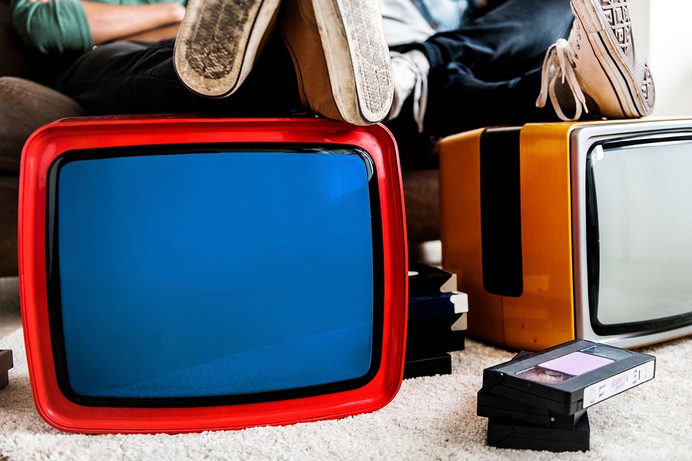 Two man sitting next to retro televisions