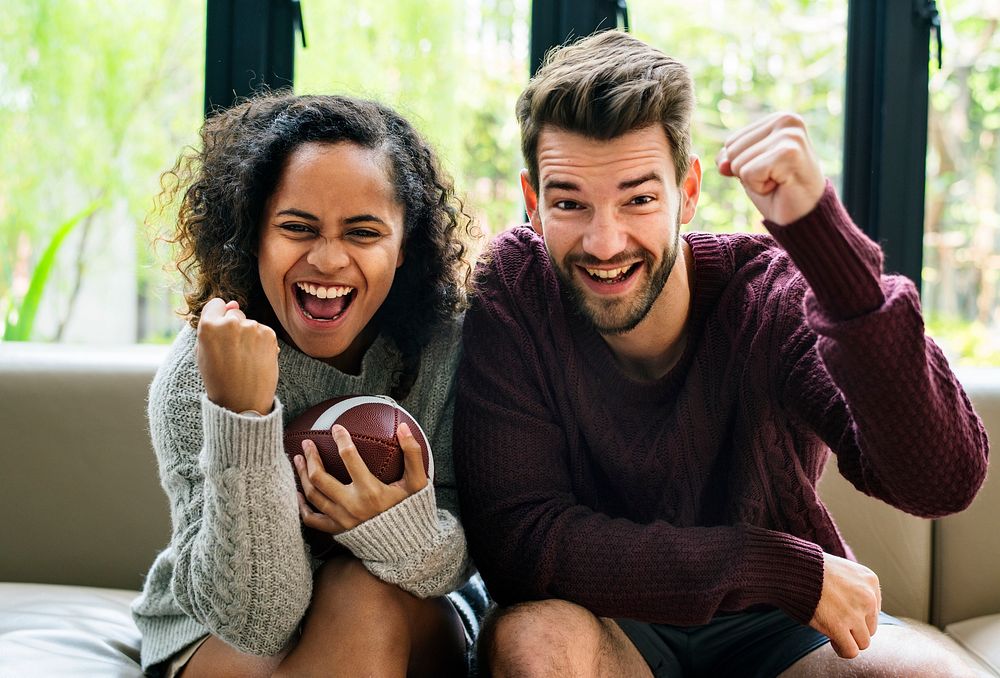 Young couple watching american football at home
