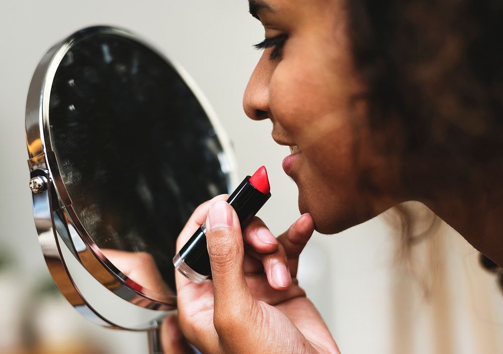 Woman putting on lipstick at mirror