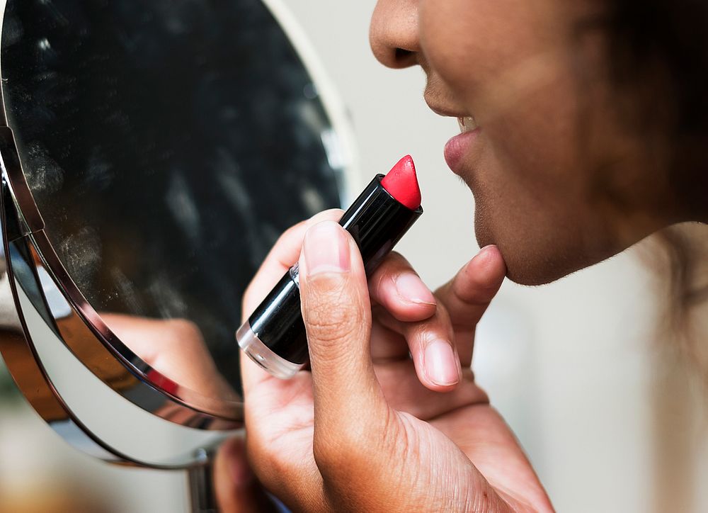 Woman putting on lipstick at mirror