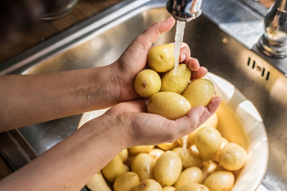 A person washing potatoes  under running water food photography recipe idea