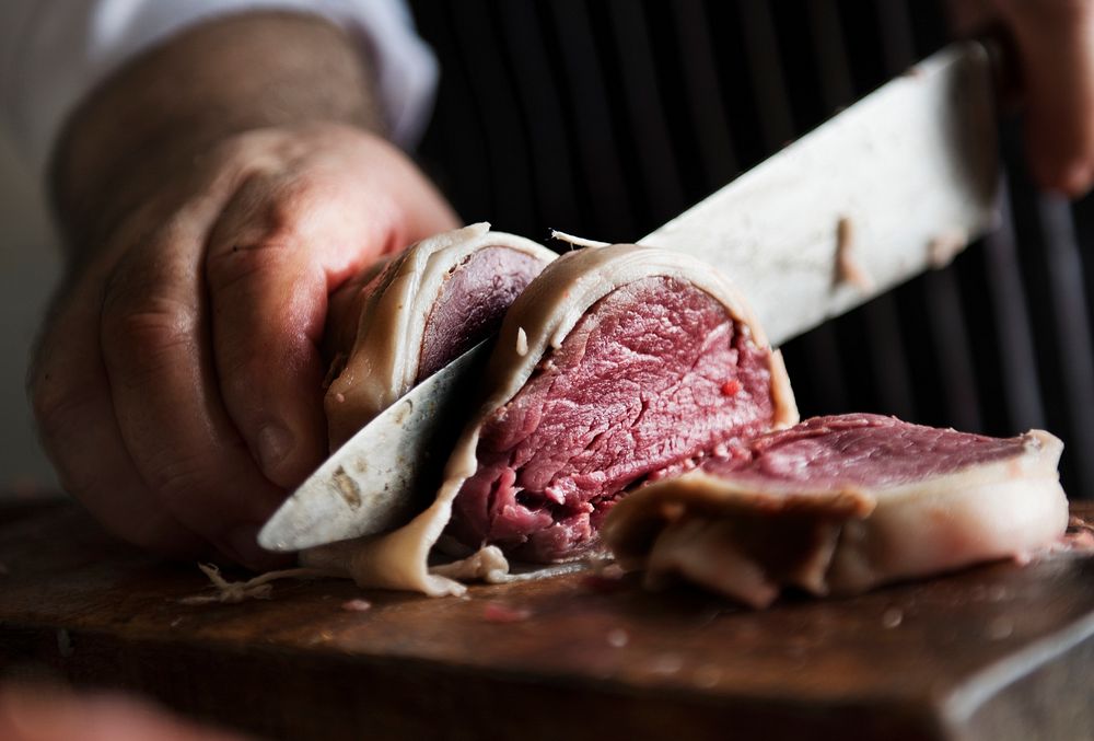 A chef working on slicing a piece of steak food photography recipe idea