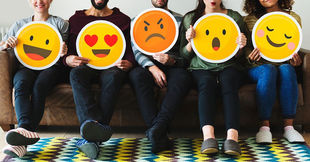 Group of diverse people holding emoticon icons