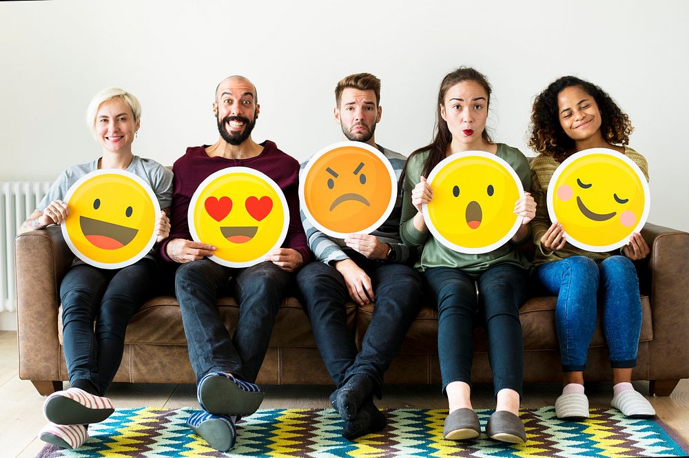 Group of diverse people holding emoticon icons