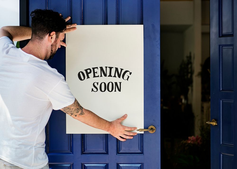 Man putting on store opening soon sign