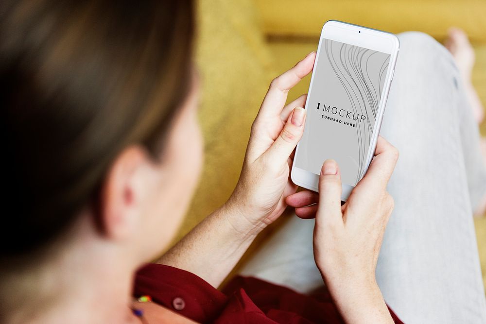 Woman sitting on a couch using a smartphone mockup