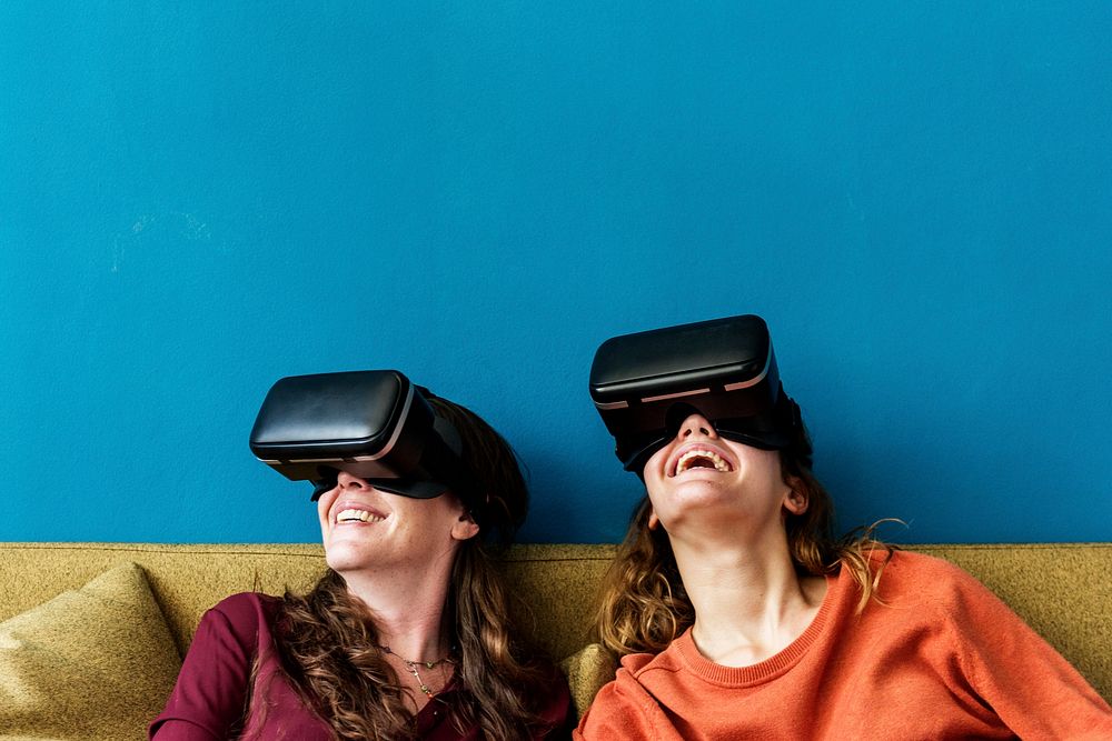 Two Caucasian woman using VR on a sofa