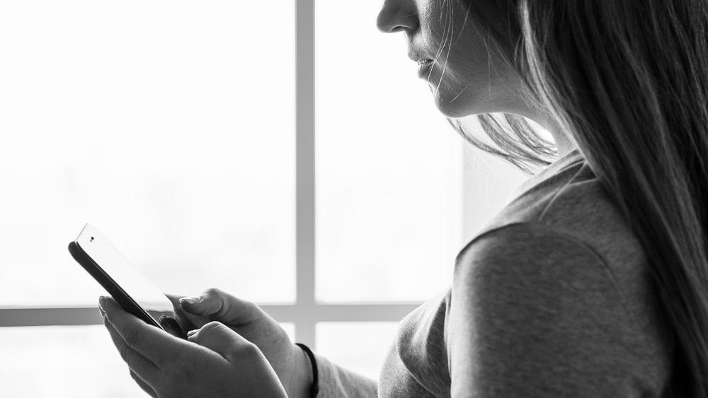 Grayscale of woman texting messaging on the phone