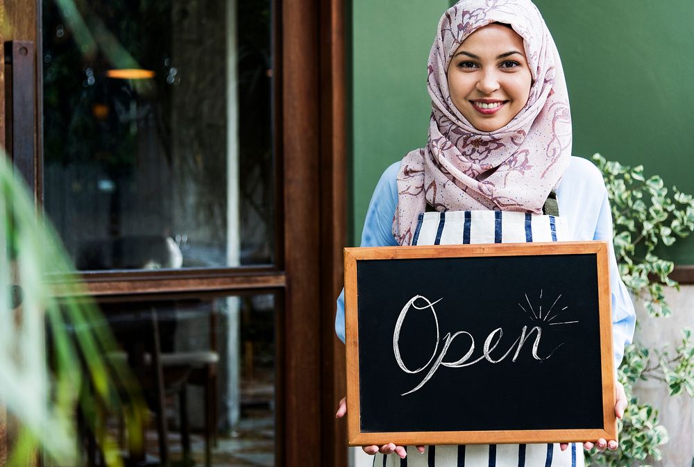 Muslim woman small business owner holding blackboard with smiling