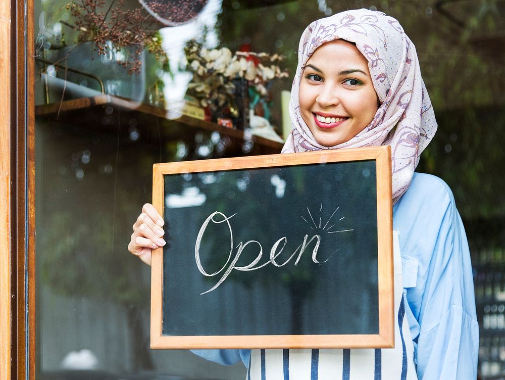 Islamic woman small business owner holding blackboard with smiling