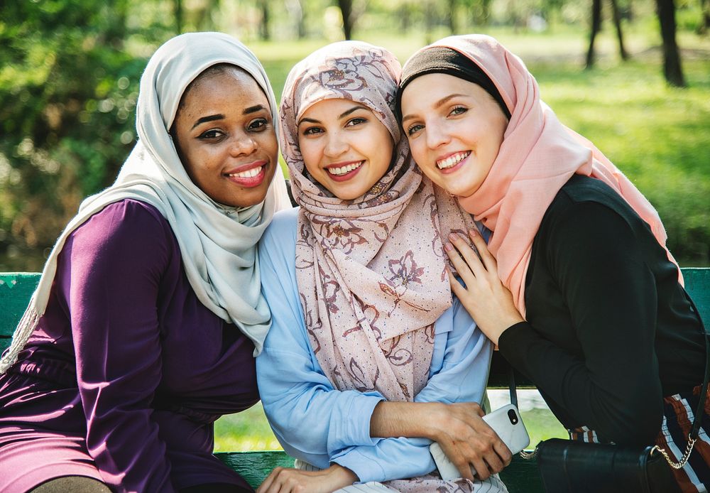 Islamic friends sitting at the park and smiling to camera