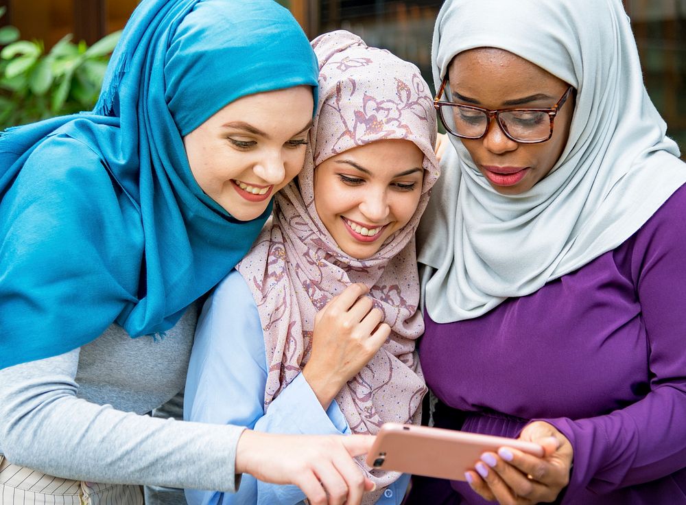 Islamic women friends looking at smart phone with smiling