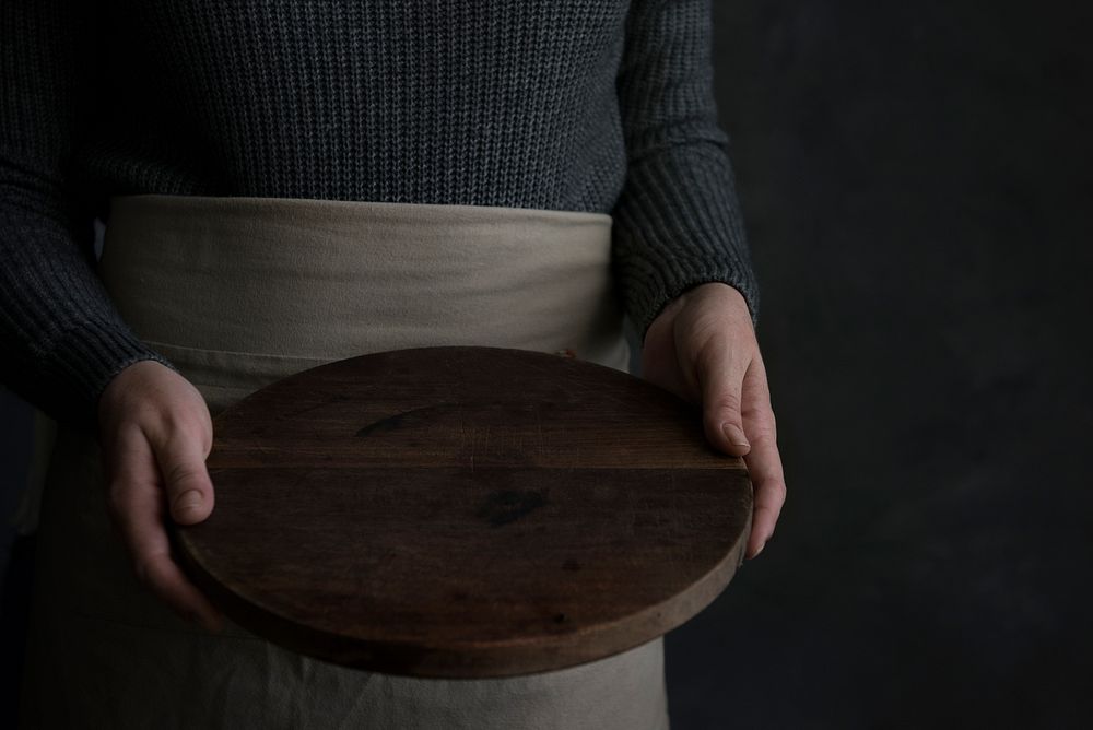 Woman in an apron holding a wooden tray