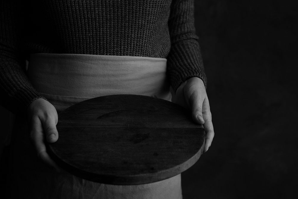 Woman in an apron holding a wooden tray