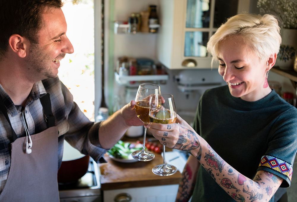 Couple having white wine while cooking in a kitchen
