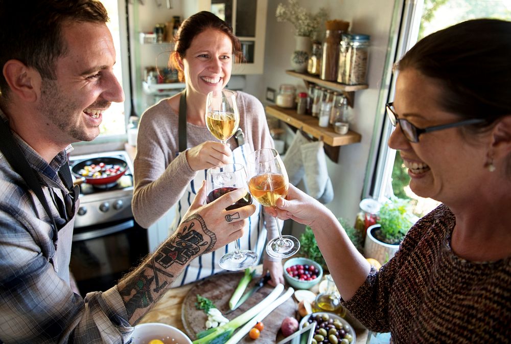 Cheerful people drinking wine in the kitchen