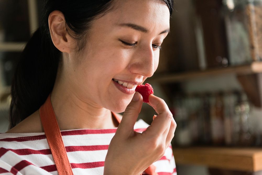 Japanese woman eating a raspberry