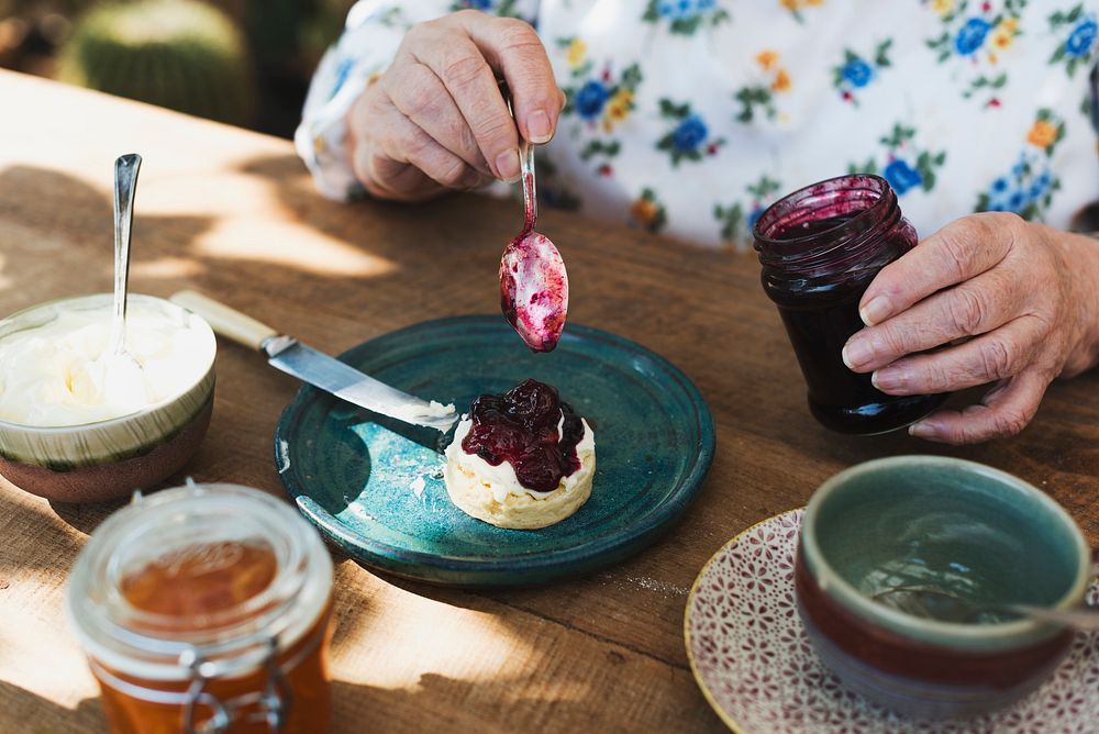 Woman putting blueberry jam on a scone