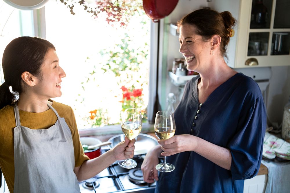 Women having white wine while cooking in a kitchen