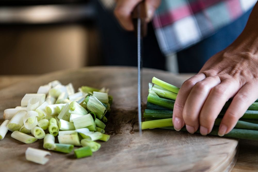 Woman chopping green onions on a cutting board