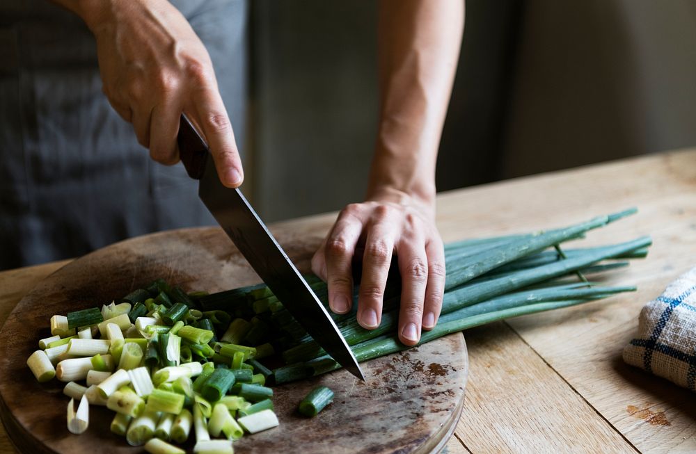 Cook chopping spring onions on a cutting board