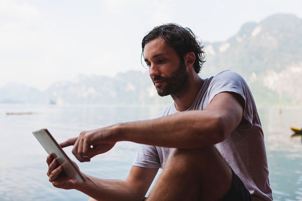 Man using his phone by a lake