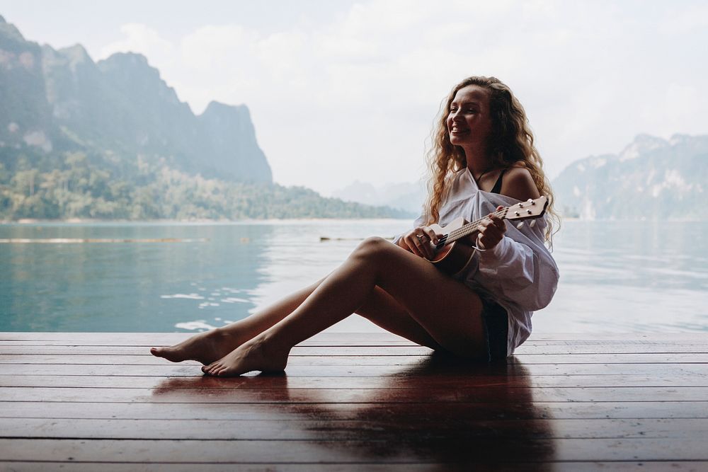 Woman playing ukulele by the water